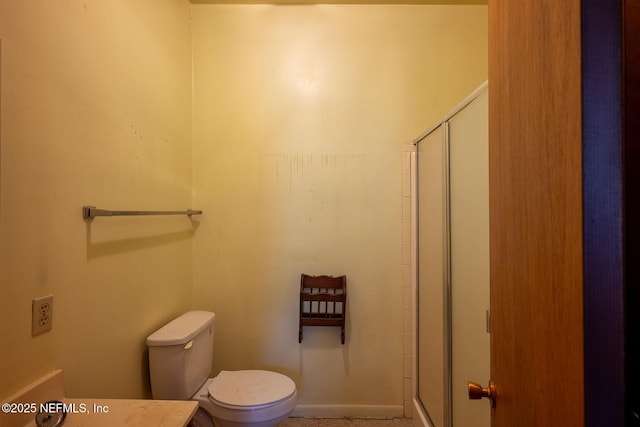 bathroom featuring a shower with door and toilet