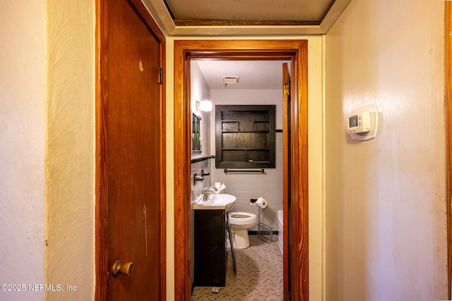 corridor featuring sink and tile walls