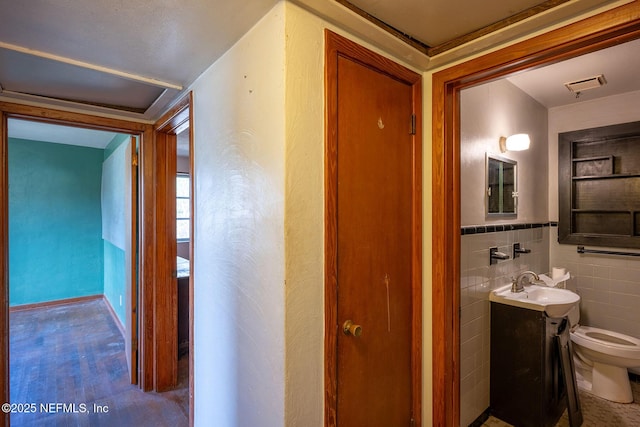 bathroom featuring vanity, tile walls, and toilet