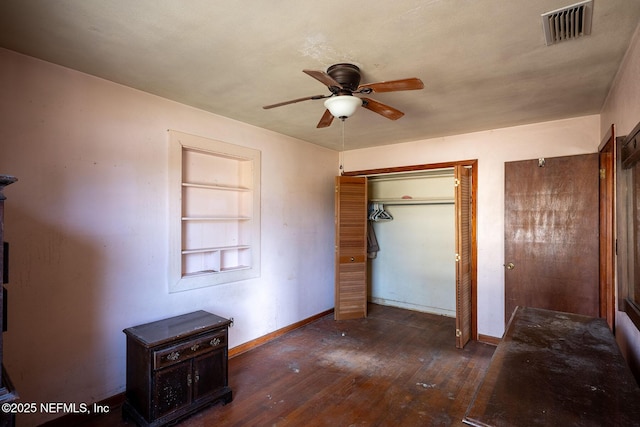 unfurnished bedroom with dark wood-type flooring, two closets, and ceiling fan