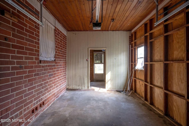 misc room with brick wall, concrete flooring, and wooden ceiling