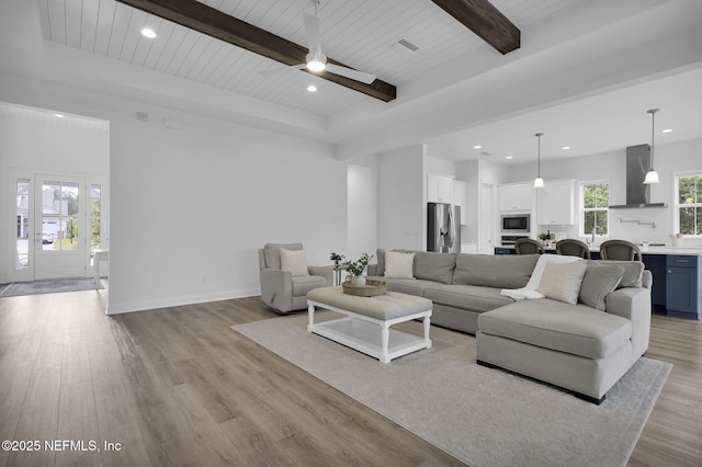 living area featuring baseboards, recessed lighting, beam ceiling, and light wood-style floors