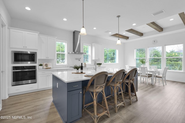 kitchen with oven, white cabinets, light countertops, built in microwave, and wall chimney exhaust hood