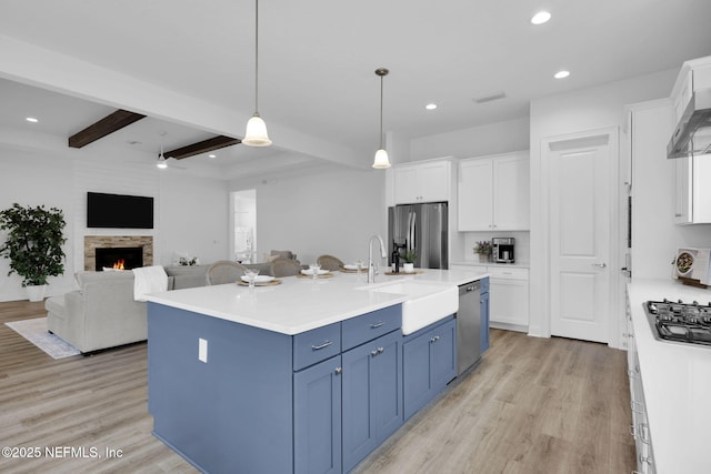 kitchen featuring decorative light fixtures, blue cabinetry, stainless steel appliances, light countertops, and white cabinetry