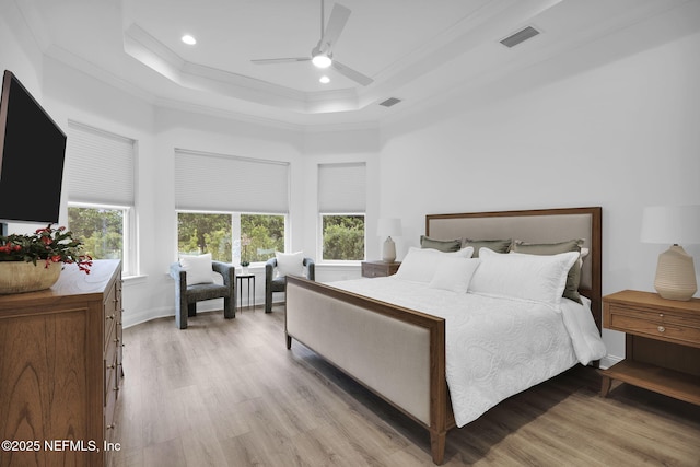 bedroom with ornamental molding, a tray ceiling, and visible vents