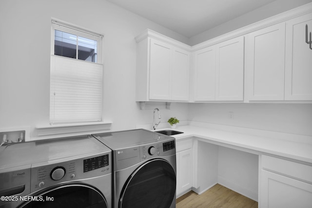 washroom with washer and dryer, cabinet space, a sink, and light wood finished floors