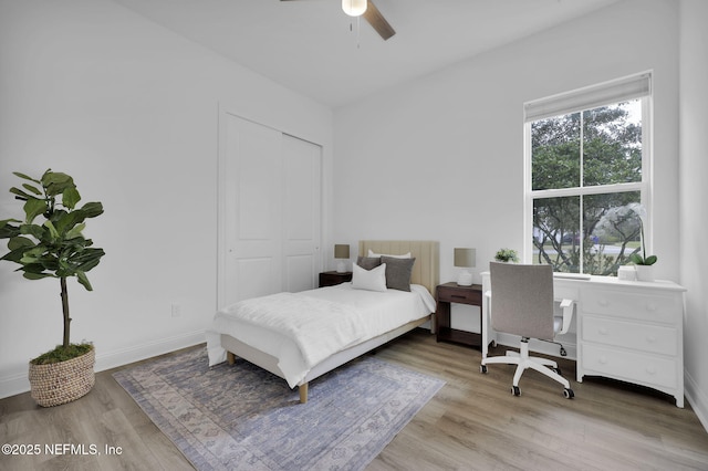 bedroom featuring a closet, light wood-type flooring, a ceiling fan, and baseboards