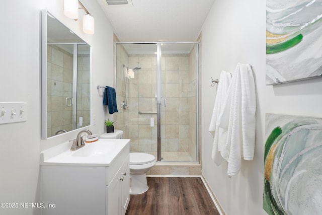 bathroom with hardwood / wood-style flooring, vanity, toilet, and a shower with door