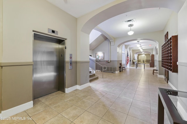 tiled foyer with elevator and lofted ceiling