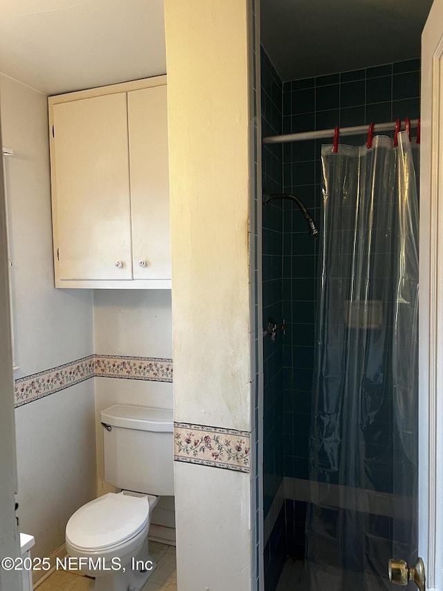 bathroom featuring tiled shower and toilet