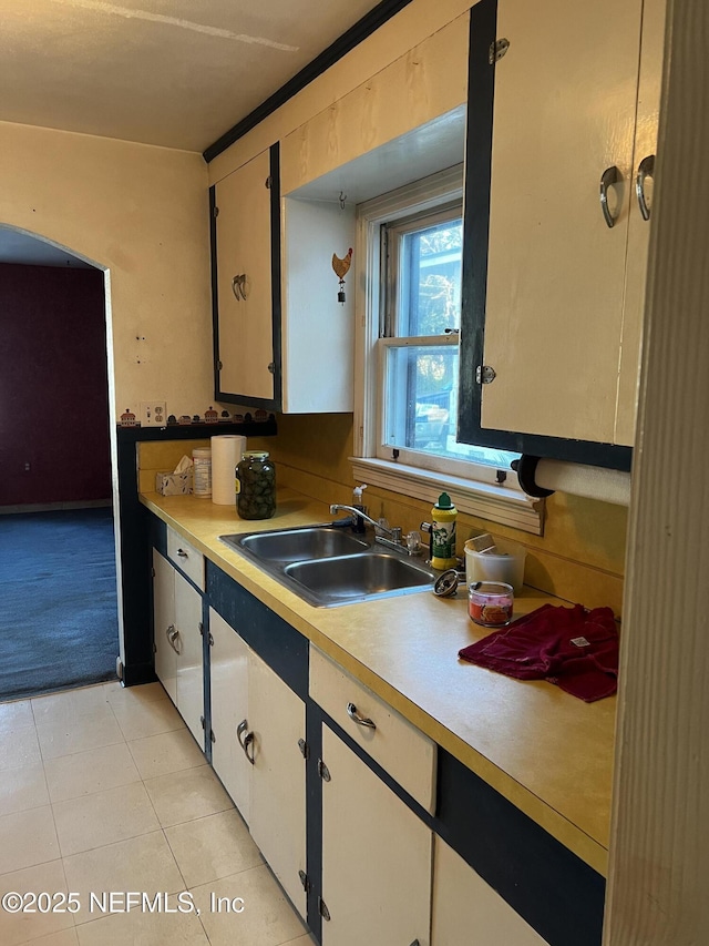 kitchen featuring sink, light tile patterned floors, and white cabinets