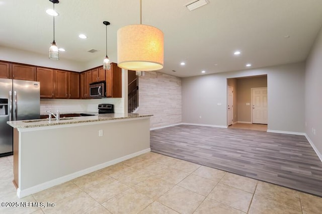 kitchen featuring sink, light stone counters, light tile patterned floors, appliances with stainless steel finishes, and pendant lighting