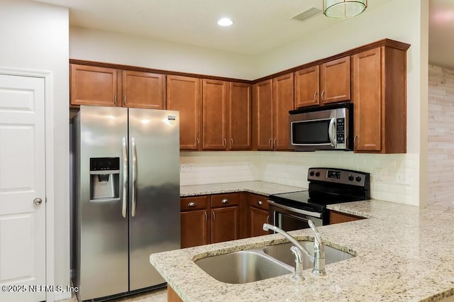 kitchen featuring appliances with stainless steel finishes, tasteful backsplash, sink, light stone counters, and kitchen peninsula