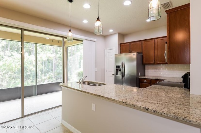 kitchen featuring sink, light stone counters, decorative light fixtures, stainless steel fridge with ice dispenser, and kitchen peninsula