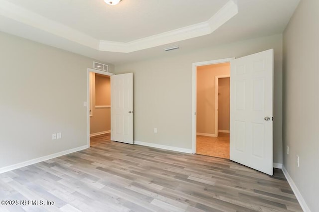 unfurnished bedroom with a raised ceiling, crown molding, and hardwood / wood-style flooring