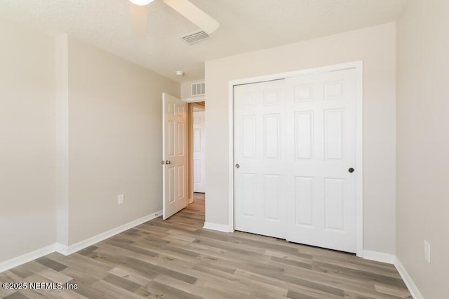 unfurnished bedroom featuring a closet, ceiling fan, and light wood-type flooring