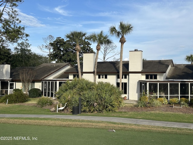 view of front facade with a front lawn and a sunroom