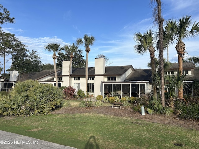 back of house with a sunroom and a lawn