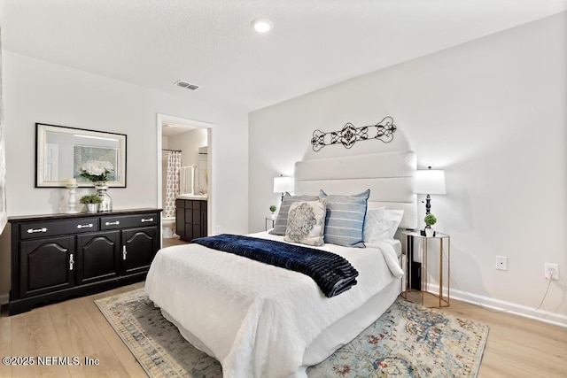 bedroom with connected bathroom and light hardwood / wood-style floors