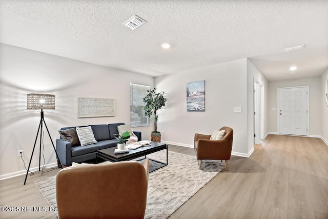 living room with a textured ceiling and light wood-type flooring