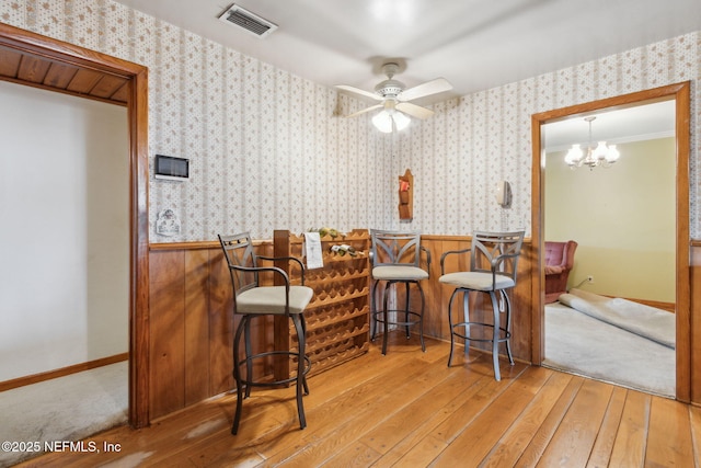 dining room with crown molding, light hardwood / wood-style flooring, ceiling fan, and indoor bar