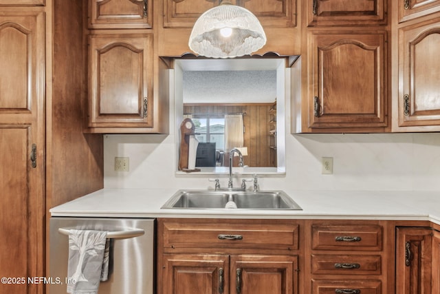 kitchen with pendant lighting, sink, stainless steel dishwasher, and a textured ceiling