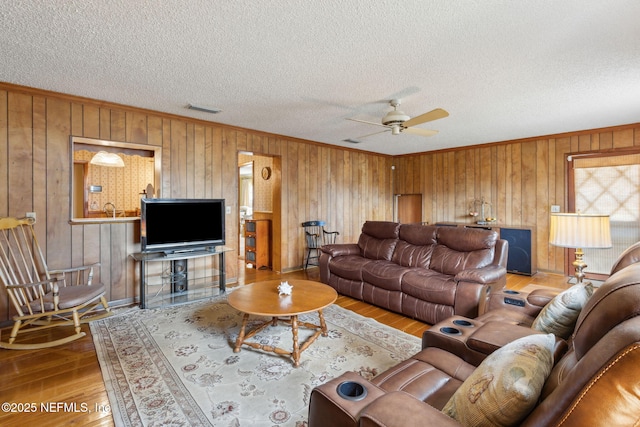 living room featuring ornamental molding, a textured ceiling, and light wood-type flooring