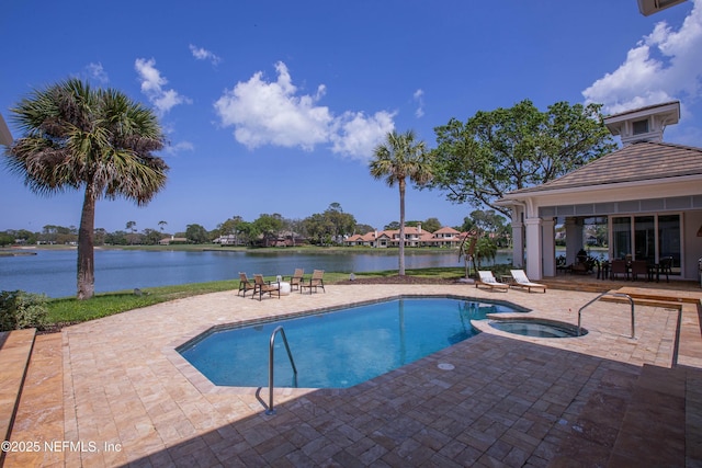 view of swimming pool featuring a water view, a patio area, and a pool with connected hot tub