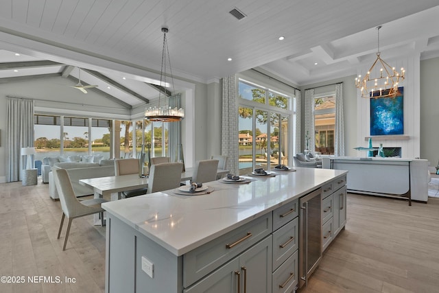 kitchen with light wood-style flooring, a kitchen island, gray cabinetry, visible vents, and beverage cooler