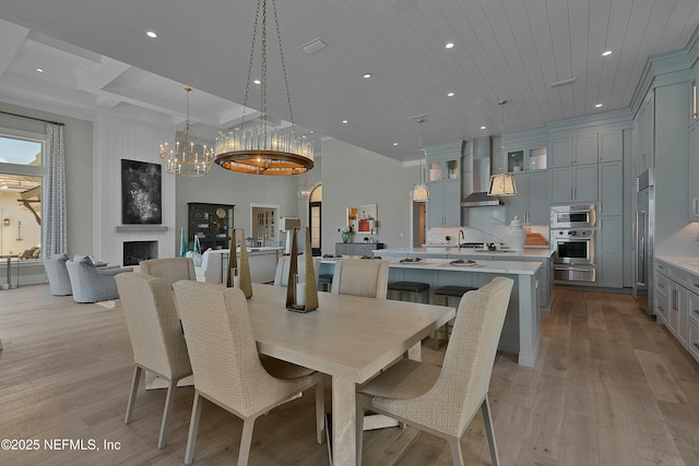 dining space featuring light wood-type flooring, a chandelier, wood ceiling, recessed lighting, and a large fireplace