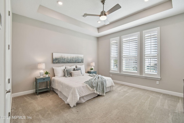 bedroom with a raised ceiling, a ceiling fan, recessed lighting, carpet flooring, and baseboards