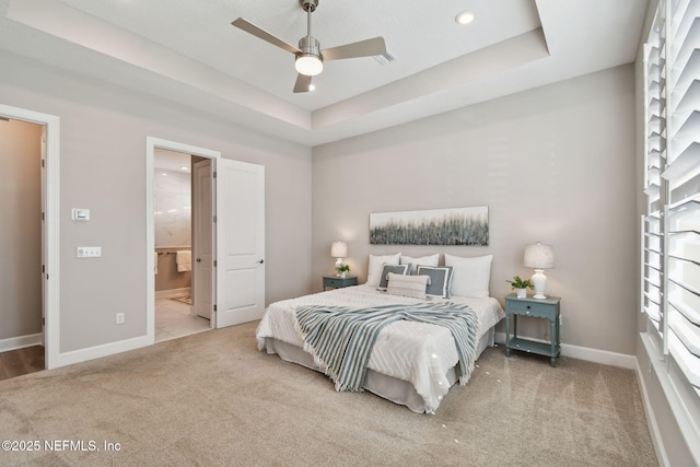 bedroom featuring baseboards, a raised ceiling, carpet, and ensuite bath