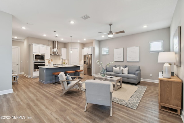 living area with baseboards, visible vents, recessed lighting, ceiling fan, and light wood-type flooring