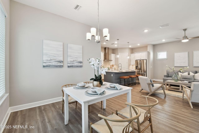 dining area featuring visible vents, ceiling fan with notable chandelier, recessed lighting, light wood-style floors, and baseboards