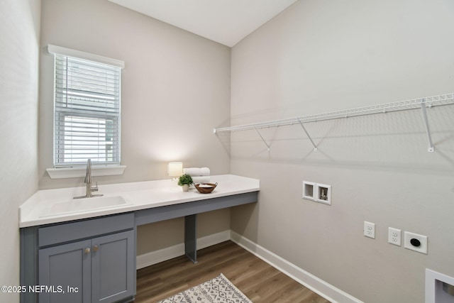 clothes washing area with electric dryer hookup, dark wood-type flooring, a sink, cabinet space, and baseboards