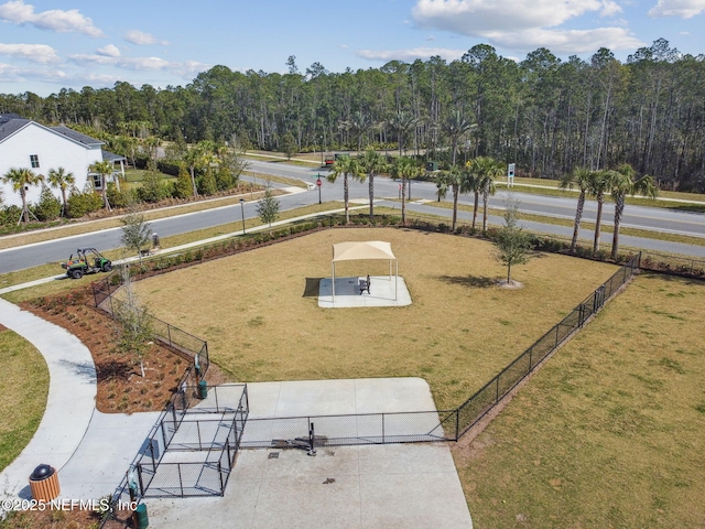 view of home's community with a wooded view, a yard, and fence