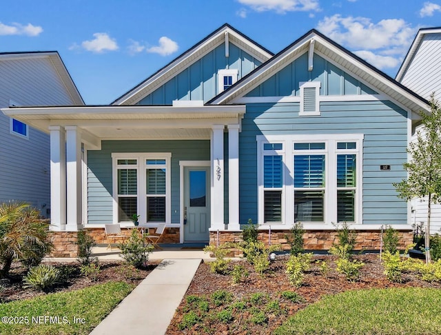 view of front of property featuring covered porch, board and batten siding, and stone siding