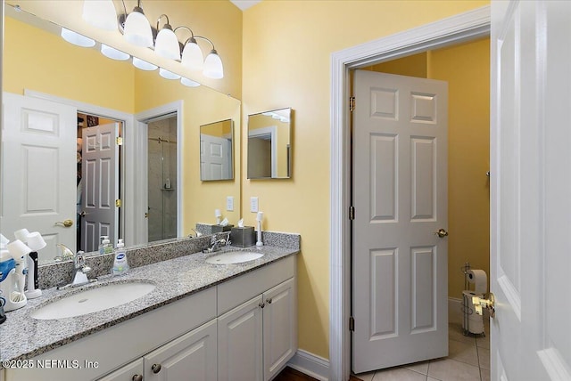 bathroom with double vanity, tile patterned flooring, a sink, and tiled shower