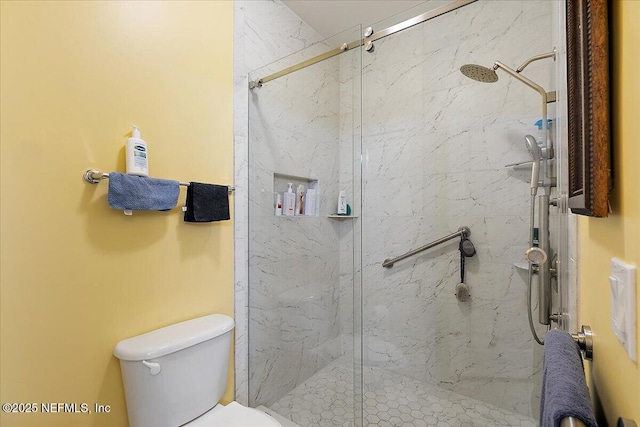 bathroom featuring toilet and a marble finish shower