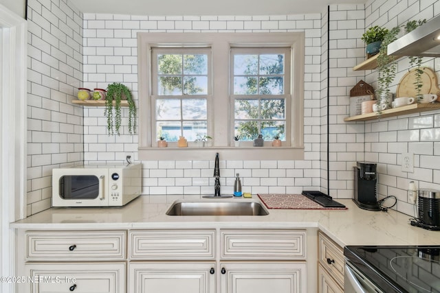758 Acosta St, Jacksonville, FL 32204 - kitchen featuring sink, backsplash, light stone countertops, and a healthy amount of sunlight