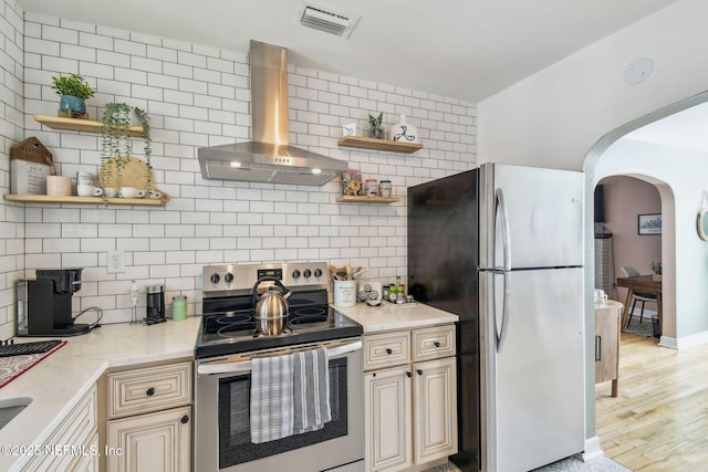 758 Acosta St, Jacksonville, FL 32204 - kitchen featuring backsplash, light stone counters, stainless steel appliances, wall chimney range hood, and light wood-type flooring