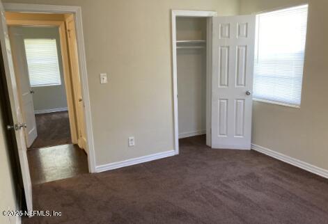 unfurnished bedroom with carpet floors, a closet, multiple windows, and baseboards