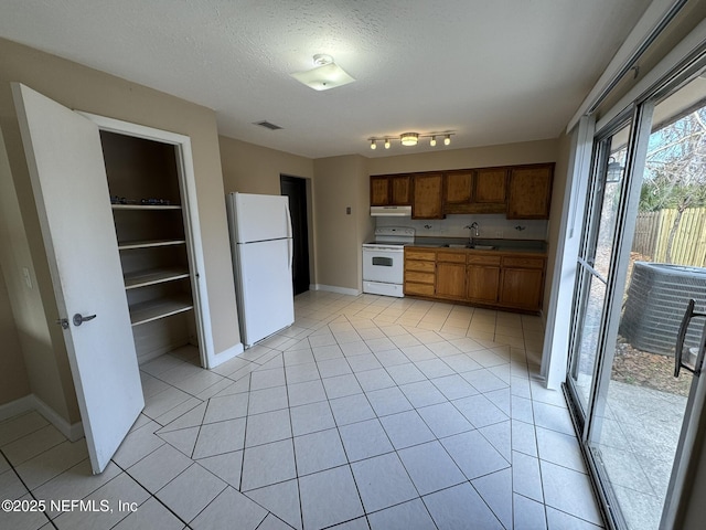 kitchen featuring white appliances, sink, a textured ceiling, and light tile patterned floors