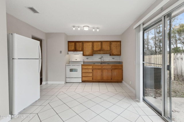 kitchen with white appliances, sink, and light tile patterned floors