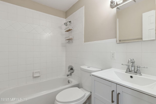 full bathroom featuring vanity, tiled shower / bath, tile walls, and toilet