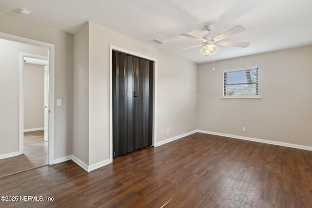 unfurnished bedroom with ceiling fan, dark hardwood / wood-style flooring, and a closet