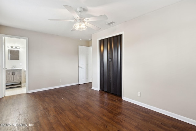 unfurnished bedroom featuring ceiling fan, connected bathroom, dark hardwood / wood-style flooring, and a closet