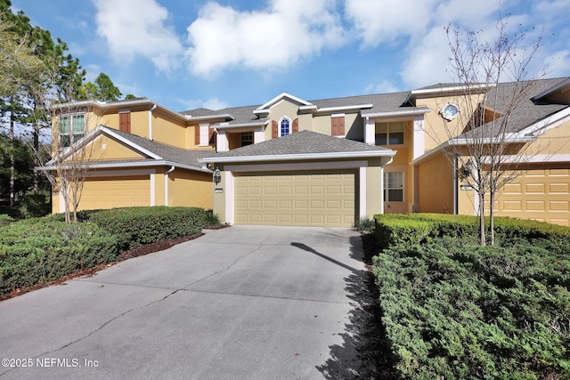 view of front of home with stucco siding, roof with shingles, concrete driveway, and an attached garage