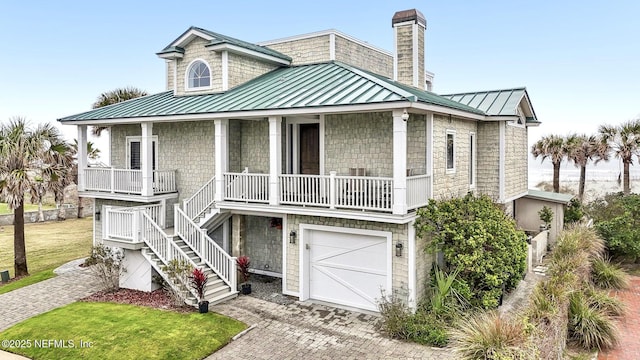 view of front of home with metal roof, a standing seam roof, covered porch, stairs, and decorative driveway