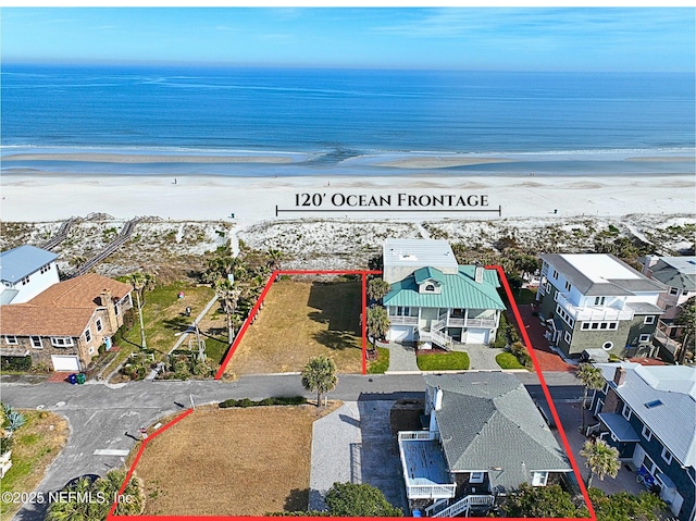 birds eye view of property featuring a water view and a beach view